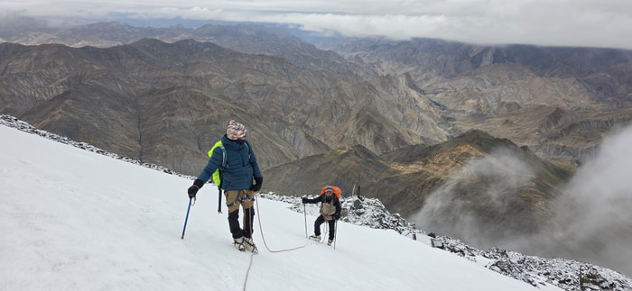 Layers of Ladakh mountains seen from the snowy summit slope.